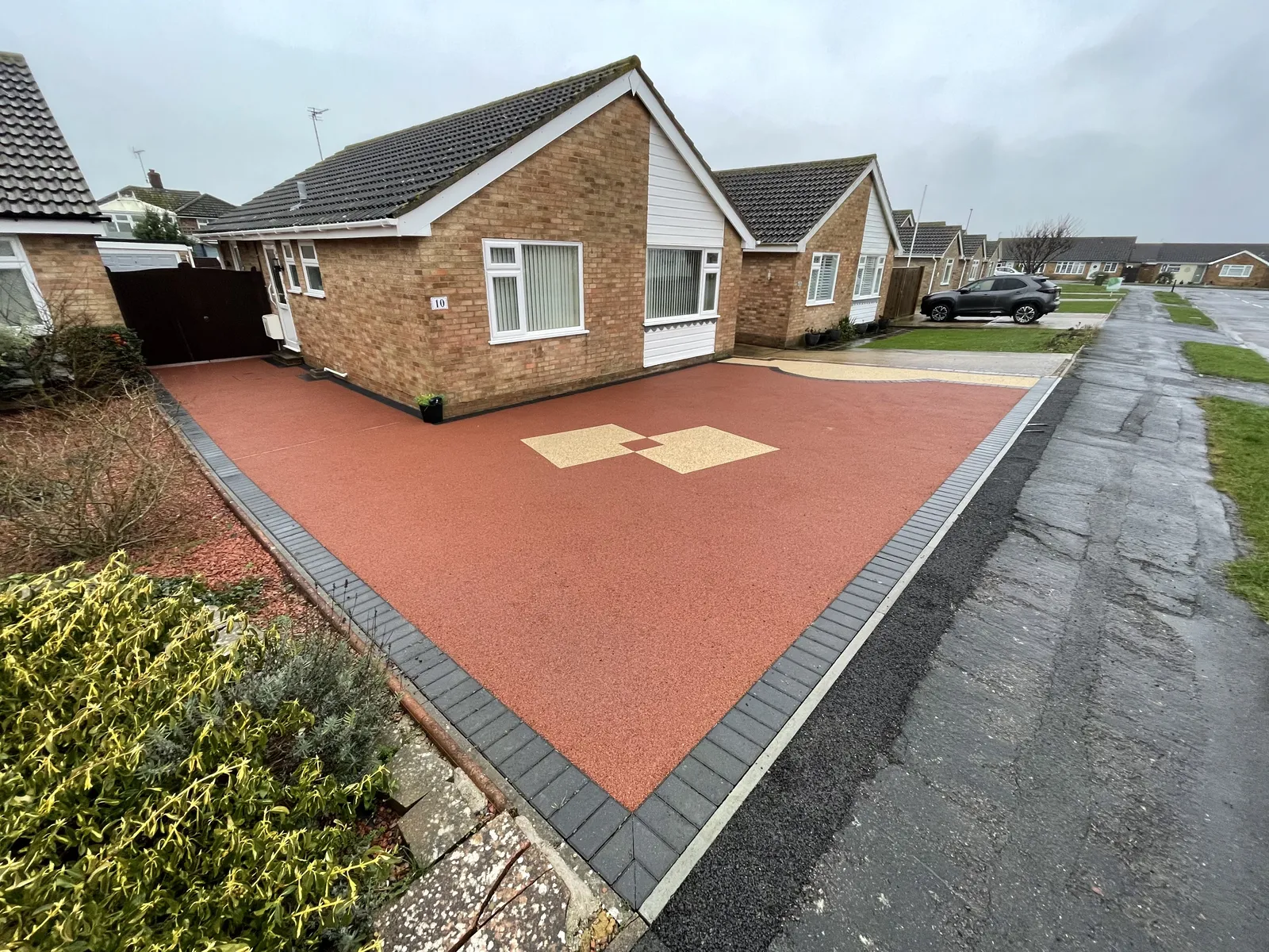 Red driveway with cream diamond detailing and dark block edging in Langney