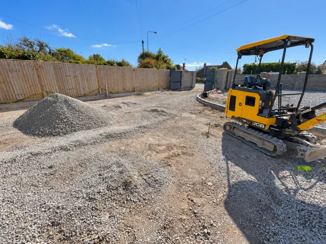 Aggregate spread across the driveway beside a mini excavator