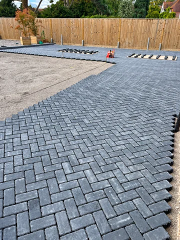 Grey block paving being laid in a herringbone pattern